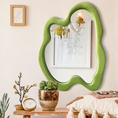 a green mirror sitting on top of a wall next to a wooden bench and potted plants