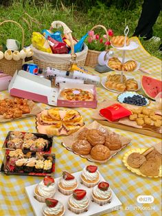 a picnic table filled with pastries and desserts on top of a checkered cloth