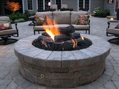 an outdoor fire pit surrounded by chairs and tables with lit candles on the patio area