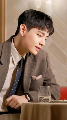 a young man sitting at a table with a glass of water in front of him