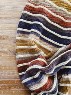 a multicolored sweater laying on top of a wooden table