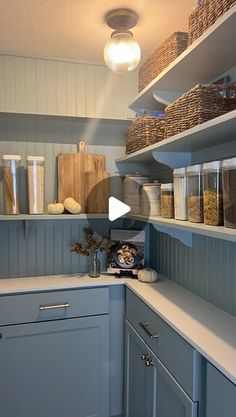 a kitchen with blue cabinets and shelves filled with containers, baskets, and other items