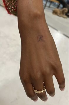 a woman's hand with a small tattoo on her left wrist and gold chain bracelet