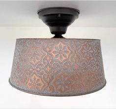 a light fixture with a metal shade hanging from it's center point on the ceiling