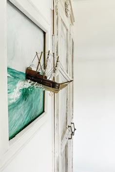 a painting hanging on the side of a door with a ship in it's center