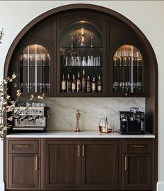 a bar with wine glasses and liquor bottles on the shelves, next to a coffee maker