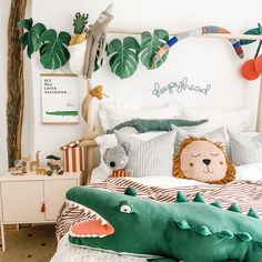 a child's bedroom decorated in green and white with stuffed animals on the bed