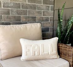 a white pillow sitting on top of a couch next to a potted plant