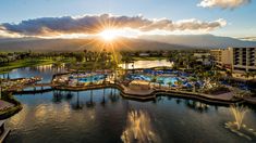 an aerial view of the resort and pool area at sunset, with mountains in the background