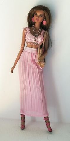 a barbie doll is wearing a pink dress and holding a purse in one hand while standing against a white wall