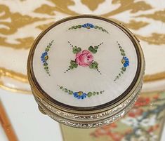 a small round box with flowers painted on it