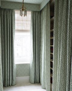 an empty room with curtains and a chandelier hanging from the ceiling in front of a window