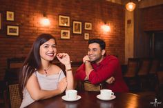 two people sitting at a table with cups and saucers