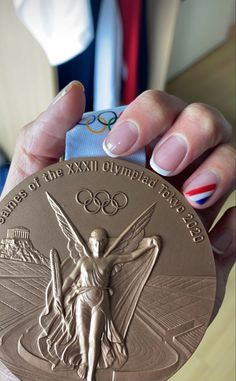 a woman's hand holding up a gold medal with an olympic symbol on it