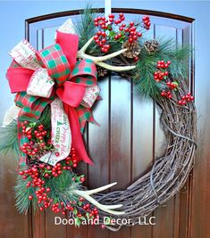 a christmas wreath with antlers and berries hanging on a door