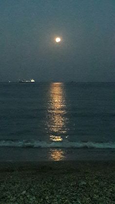 the moon shines brightly over the ocean as it reflects in the water