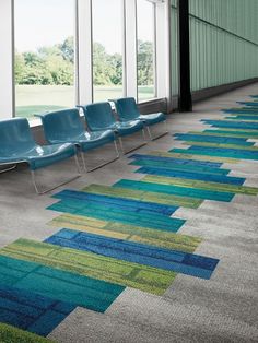 an empty waiting area with blue chairs and green carpet