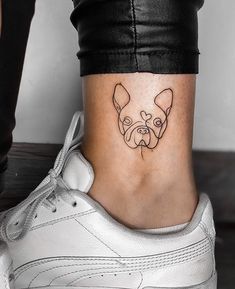 a small dog's face on the ankle is shown in this tattoo style photo