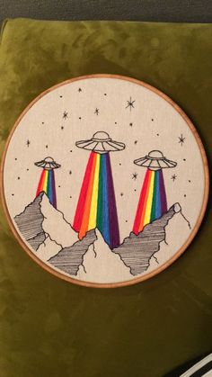 an embroidered patch with two rainbows in the sky and stars above them on a green velvet surface