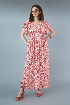 a woman in a red and white dress standing with her hands on her hips, looking at the camera