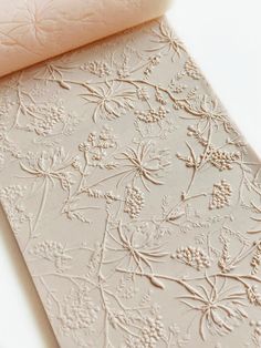 a close up of a piece of paper with flowers on it next to a roll of fabric