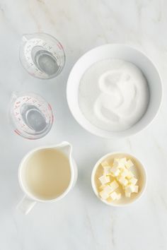 ingredients for making cheese sit in bowls on a marble counter top with measuring cups and spoons