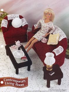 a barbie doll sitting on a red chair in a living room with white crocheted furniture