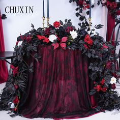 a table topped with red and white flowers on top of a black cloth covered table