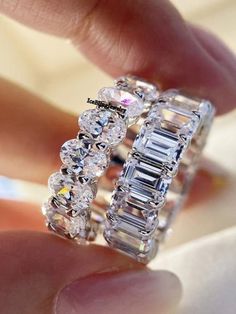 a woman's hand is holding a ring with three rows of diamonds on it