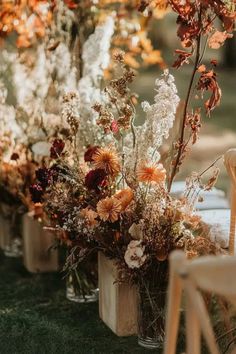 an arrangement of flowers in vases sitting on top of a table next to chairs