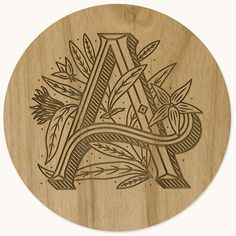 a wooden coaster with the letter a surrounded by leaves