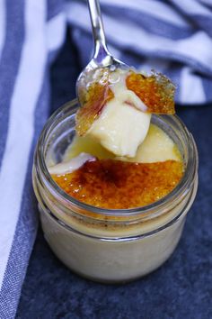 a spoon with some food in it on top of a glass jar next to a towel