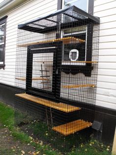 a bird cage sitting on the side of a house