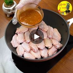 a person pouring sauce into a pan filled with chicken wings