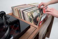 a record player is picking up records from a shelf