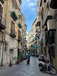 a man riding a scooter down a street next to tall buildings with balconies