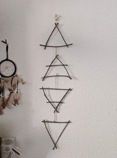 two wall hangings made out of sticks and some other things on the wall next to each other