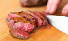 someone slicing up some meat on a cutting board