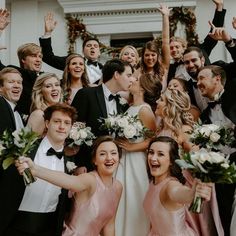 a group of people standing next to each other in front of a white building holding bouquets