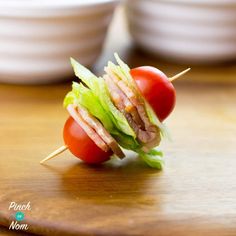 a close up of a sandwich on a wooden cutting board with tomatoes and lettuce