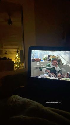 an open laptop computer sitting on top of a bed in a room with christmas lights