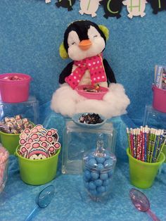 a penguin sitting on top of a table filled with candy