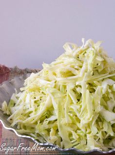 shredded cabbage in a metal bowl on a cloth tablecloth with a spoon next to it