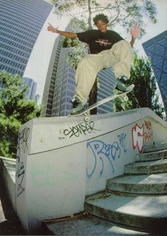 a man riding a skateboard down the side of a cement wall with graffiti on it