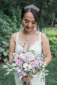 a woman in a wedding dress holding a bouquet of flowers and smiling at the camera