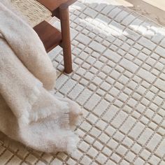 a chair with a blanket on top of it next to a wooden table and floor