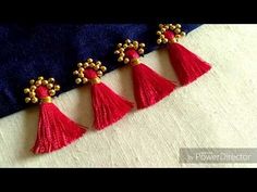 three red tassels are hanging from a blue piece of cloth with gold accents