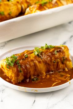 an enchilada on a plate with sauce and garnish