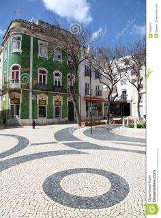 a building that is green and white in the middle of a cobblestone street