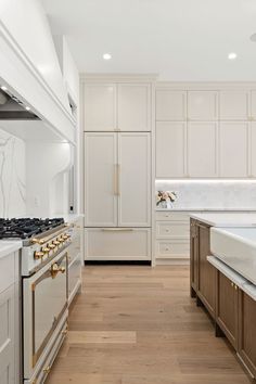 a large kitchen with white cabinets and wood flooring, along with an island in the middle